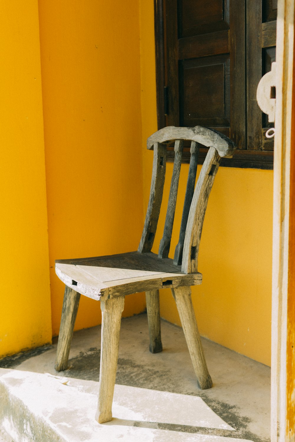 노란 벽 옆에 갈색 나무 의자