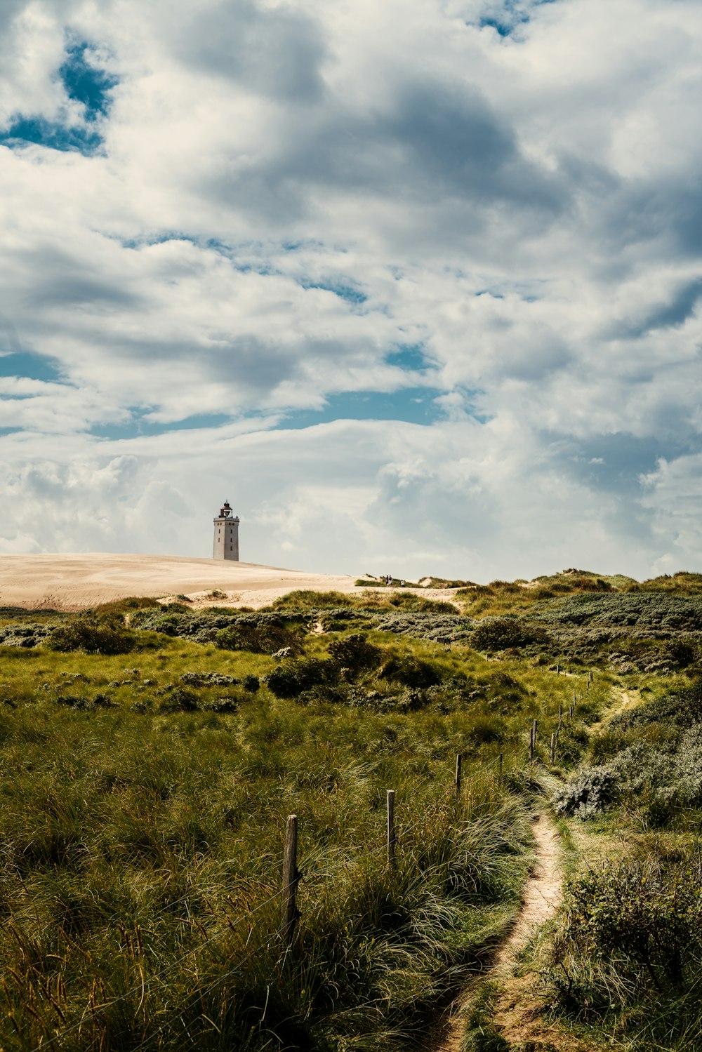 white lighthouse on green grass field under cloudy sky during daytime