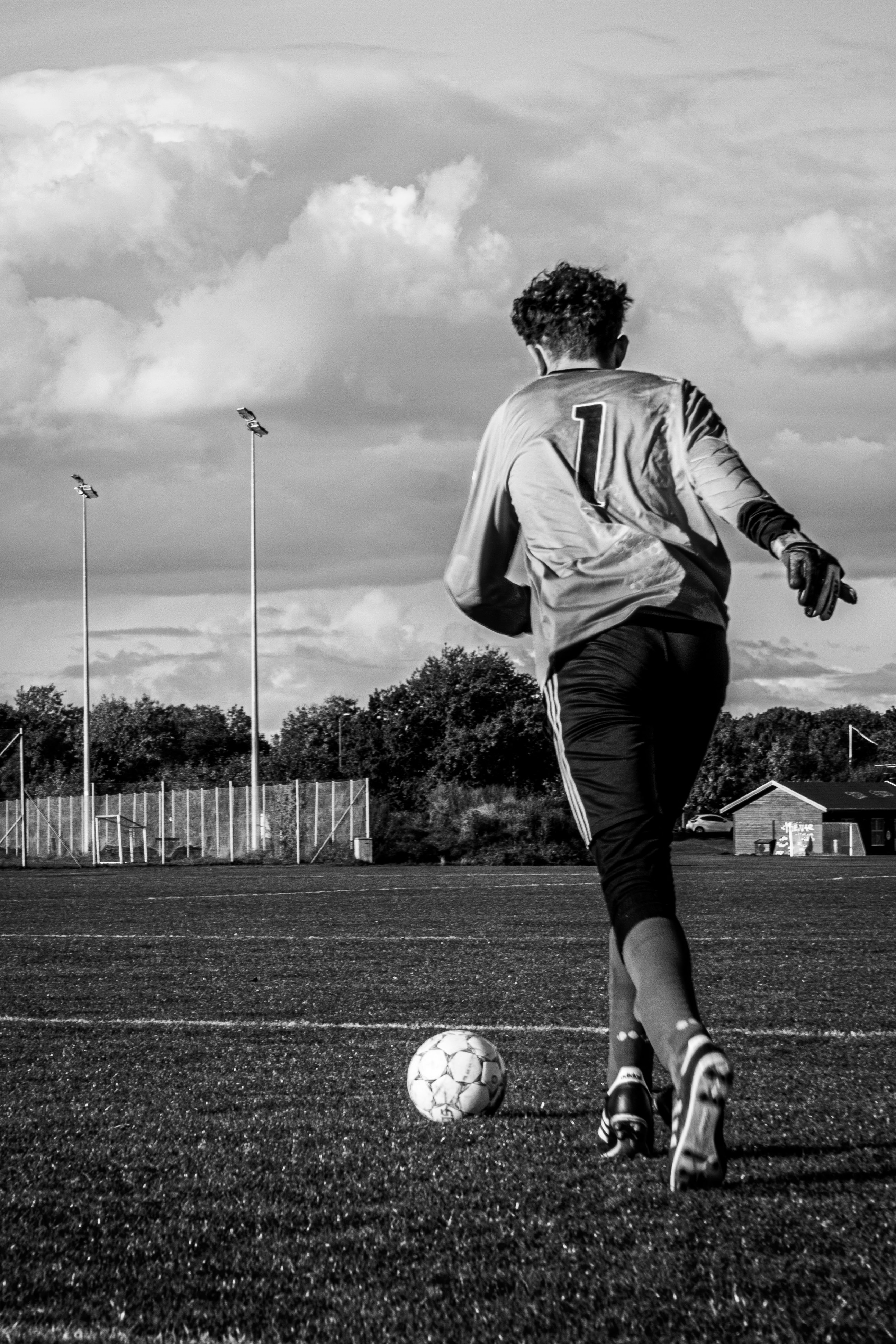 man in white long sleeve shirt playing soccer in grayscale photography