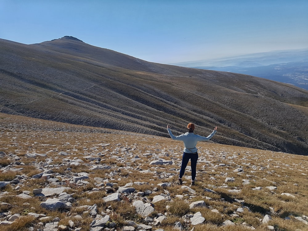 man in white long sleeve shirt standing on rocky field during daytime