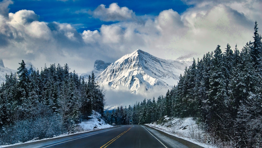 gray asphalt road near snow covered mountain during daytime