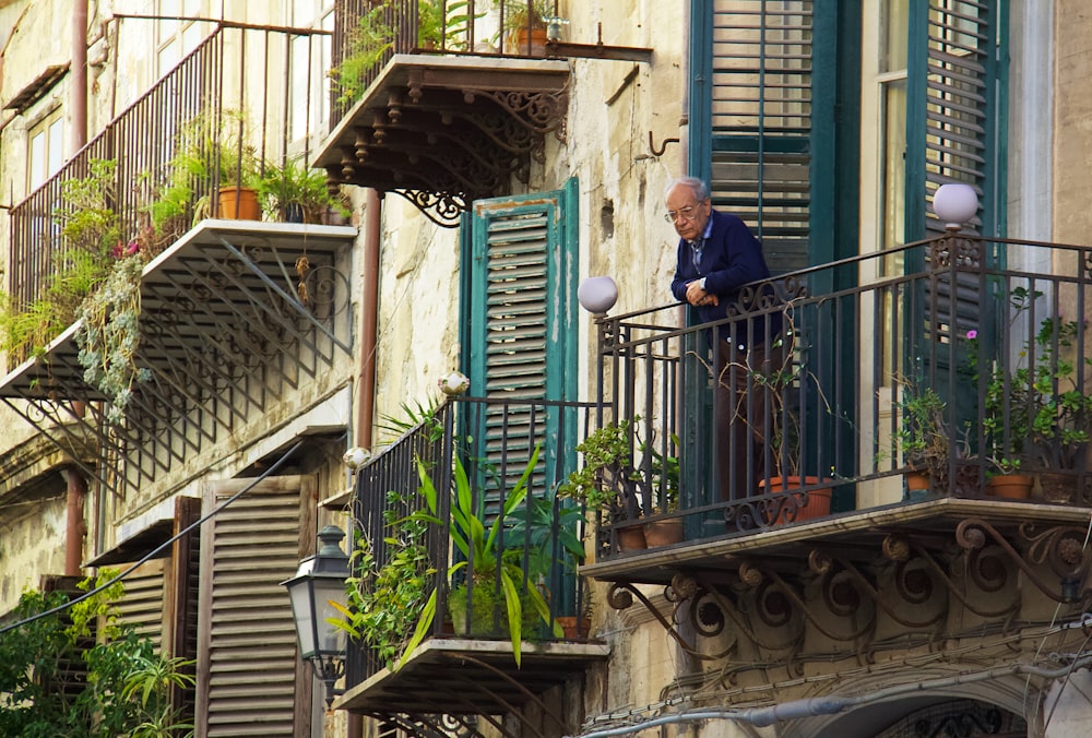 Mann in blauer Jacke steht auf dem Balkon