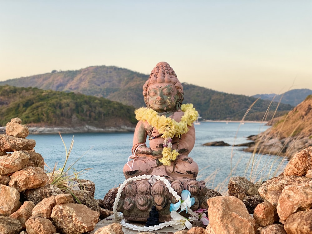 woman in yellow dress sitting on brown rock near body of water during daytime