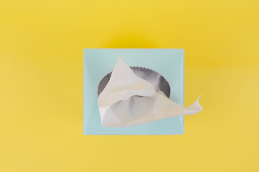 white paper boat on yellow surface, White tissue paper from the blue tissue box. Top view