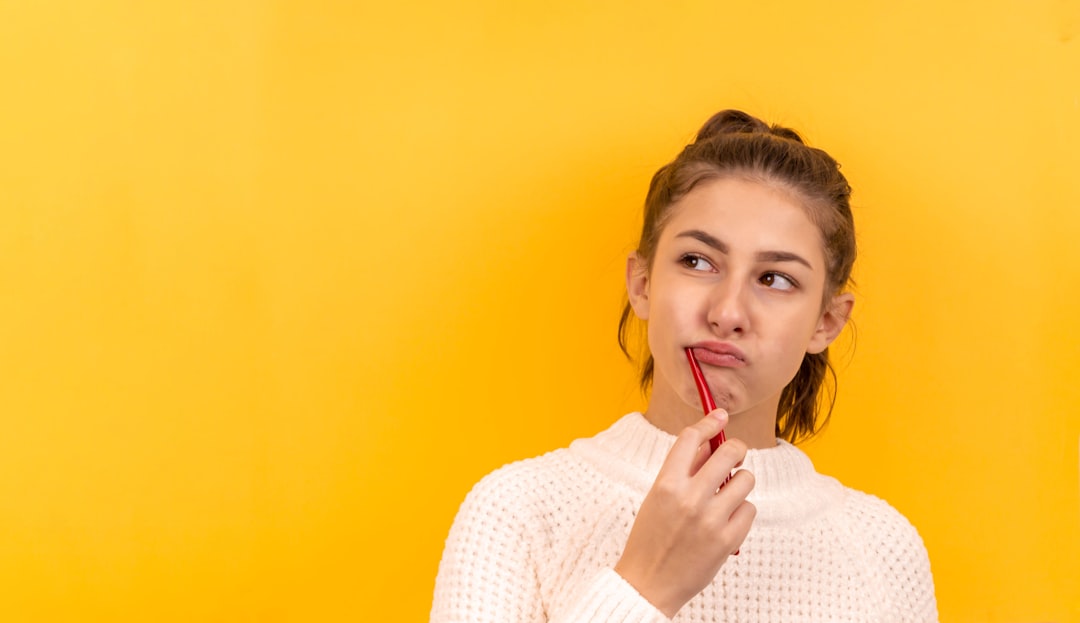 Portrait of a beautiful girl on a yellow background, who is brushing her teeth and is thinking about something. Place for an inscription. Portrait. Dentistry