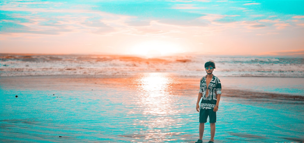 man in black and white jacket standing on sea shore during sunset