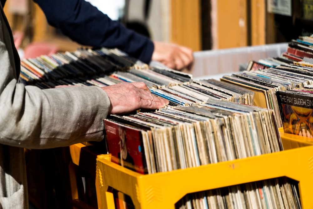 homme en chemise à manches longues grise tenant des livres