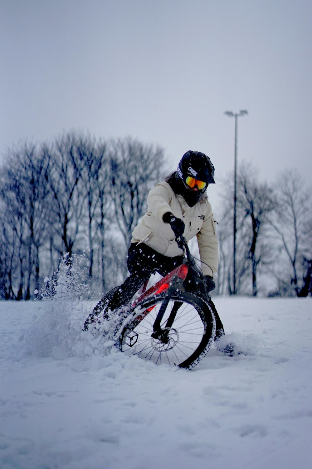 uomo in giacca bianca che cavalca su una bici BMX nera su un terreno innevato durante il giorno