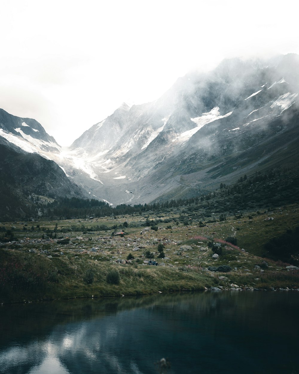 green grass field near lake and snow covered mountains during daytime