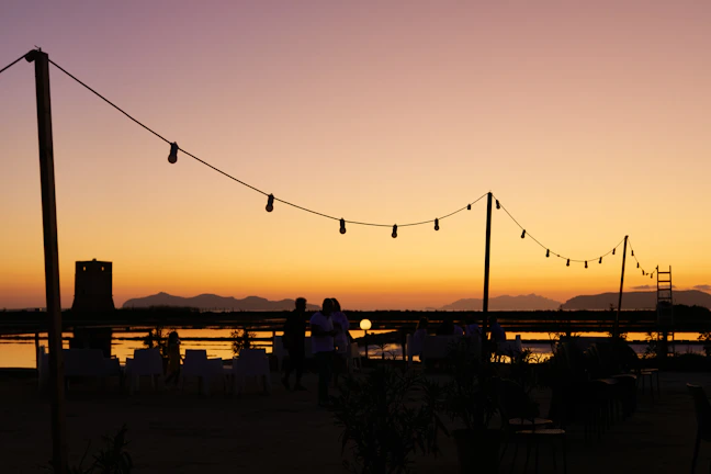 A serene outdoor event scene at sunset with tasteful lighting and decorations.