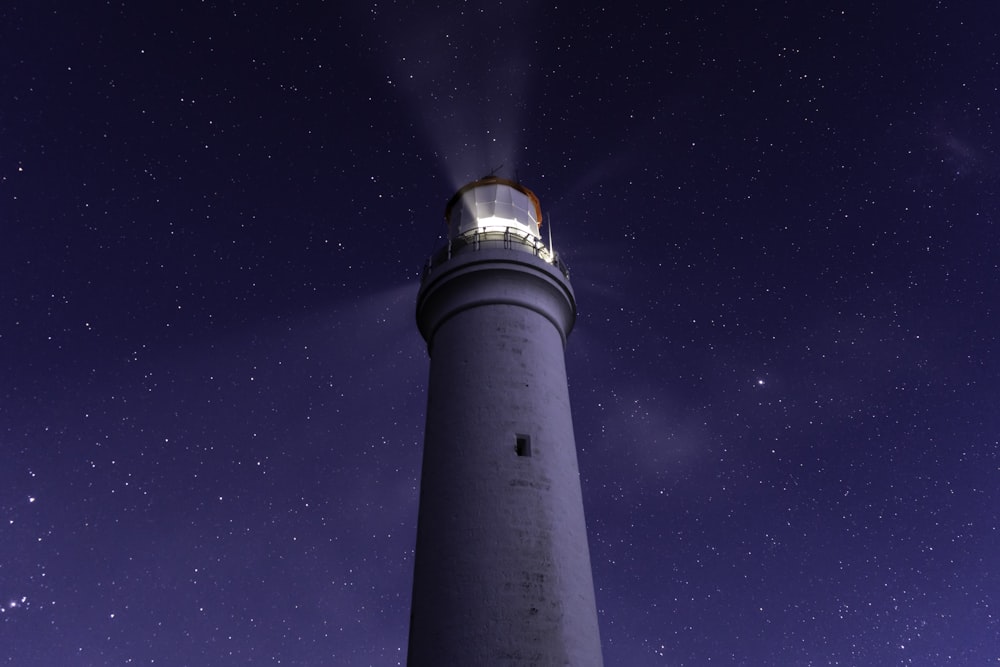 torre de luz branca sob o céu azul durante a noite