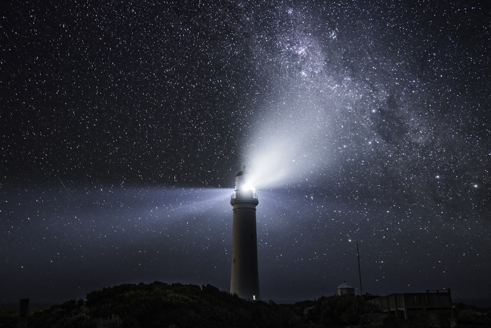 um farol sob um céu noturno cheio de estrelas