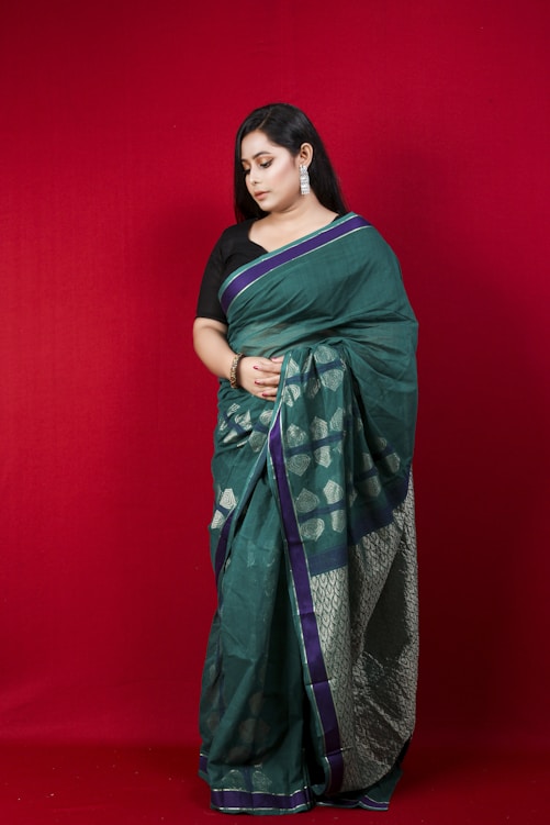 woman in green and blue sari standing beside red wall