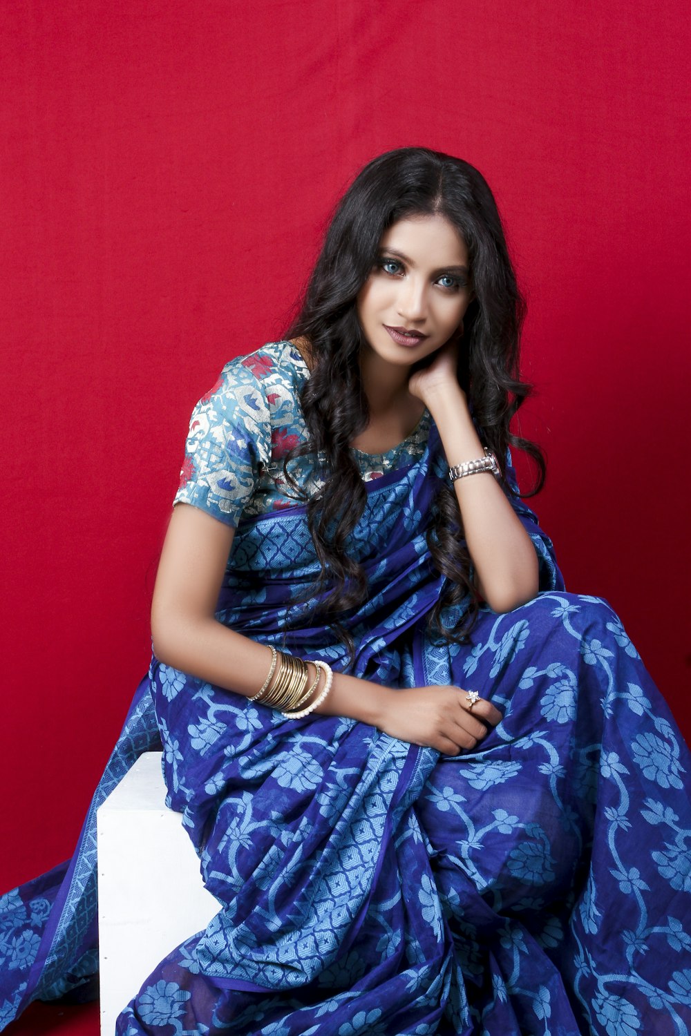 woman in blue and white floral dress sitting on white textile