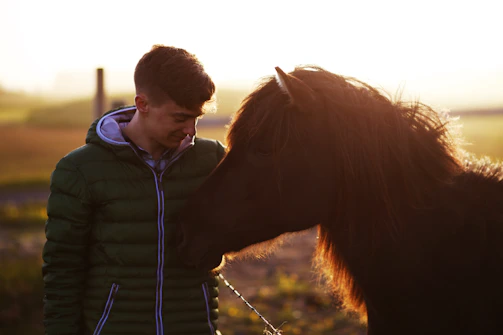 A rider and horse pausing together in the wilderness, surrounded by soft golden light.