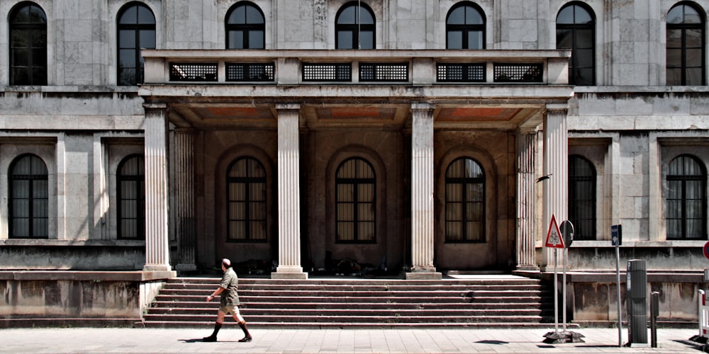 woman in black and white striped shirt and black pants walking on sidewalk near brown concrete