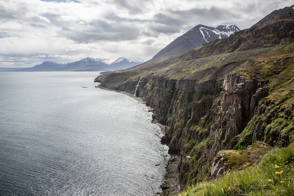 green and brown mountain beside body of water during daytime