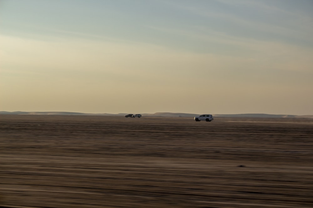 a couple of trucks driving across a desert field