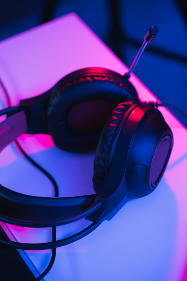 Overhead view of a modern gaming setup with a mechanical keyboard, gaming mouse, and headphones on a dark wooden desk, illuminated by soft blue ambient lighting