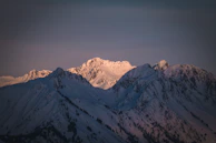 Snow-capped peaks glowing softly at sunrise above a quiet valley.