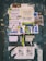 A weathered bulletin board covered with a variety of overlapping paper fliers and posters. The advertisements include rental listings, event notices, and service offers. The papers are in various stages of wear, with some crumpled and others torn. There is visible text in Spanish and a mix of graphics including logos and images. The background is a faded, chipped surface with graffiti around the edges.