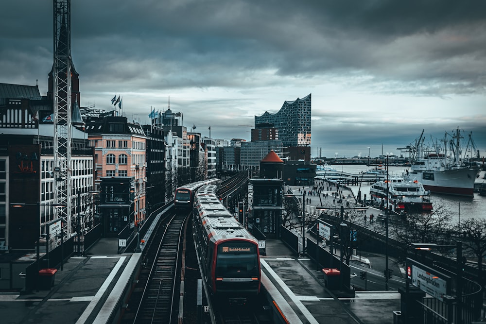 red and black train on rail road near city buildings during daytime