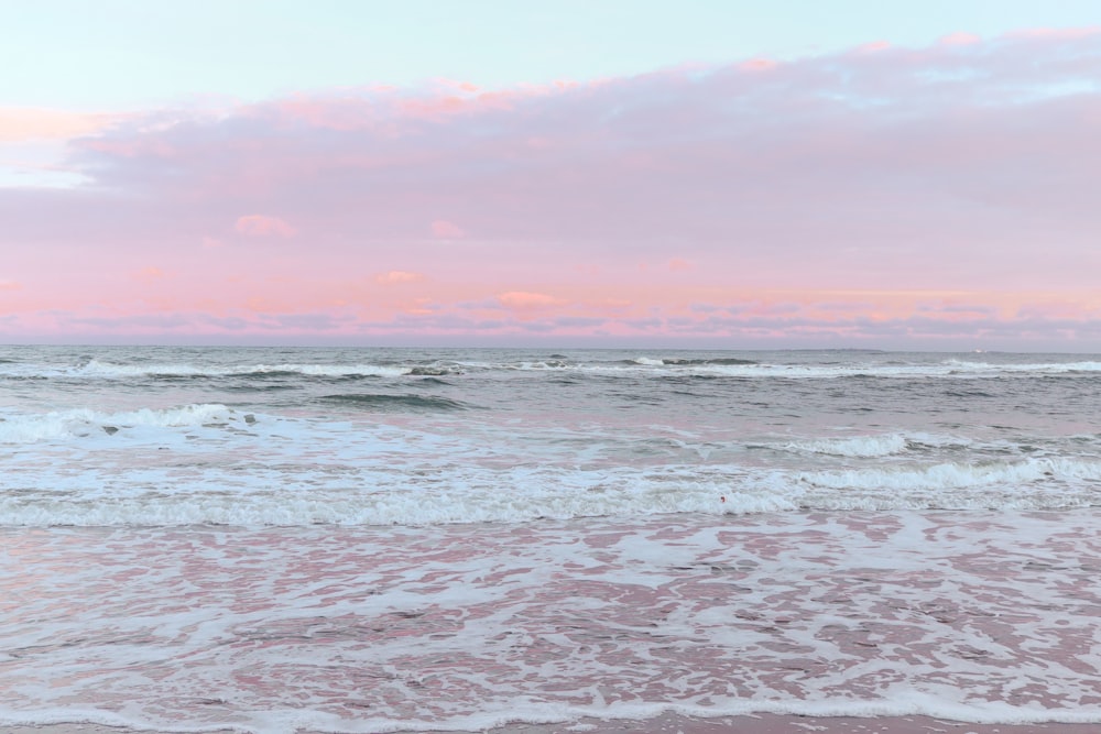 ocean waves crashing on shore during sunset