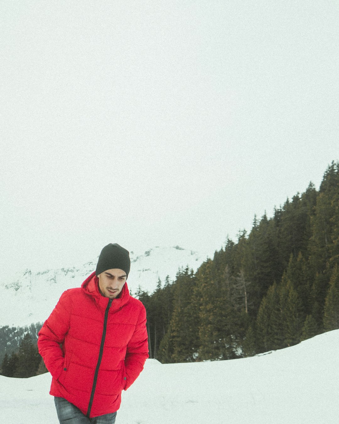 person in red winter jacket standing on snow covered ground during daytime
