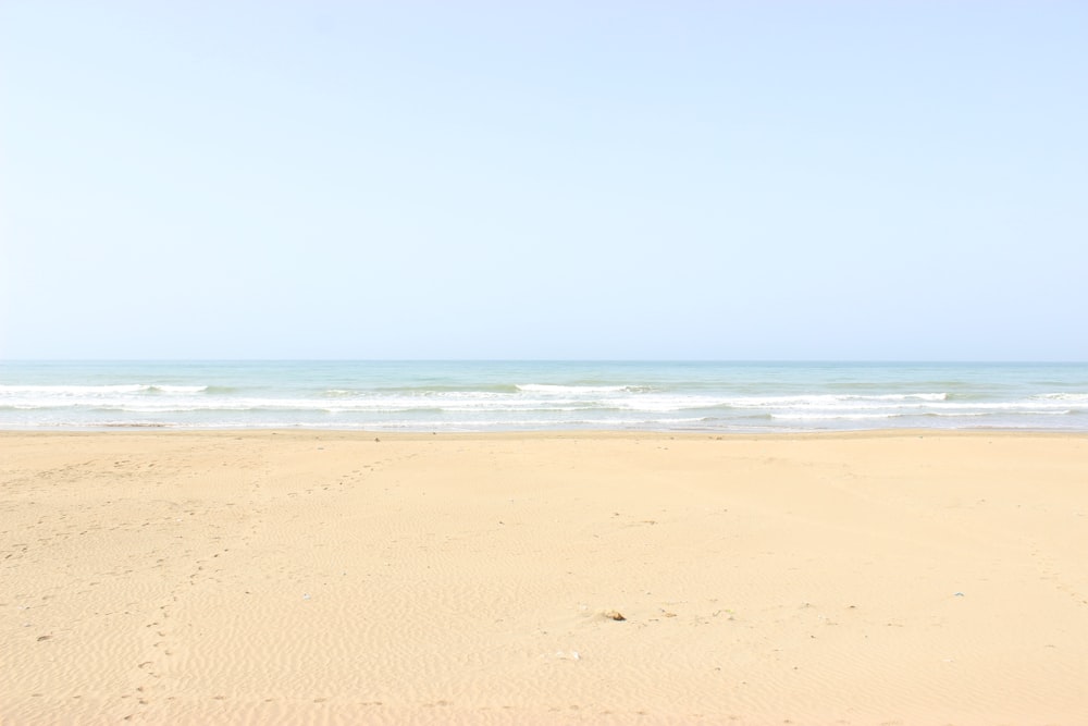 brown sand near body of water during daytime