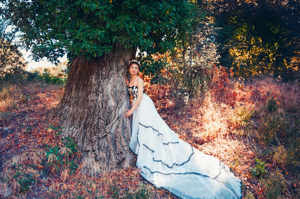 woman in white dress sitting on brown tree trunk