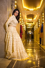A sophisticated woman in an elegant dress, smiling warmly in a luxurious setting.