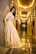 A stylish woman in a sleek formal gown standing gracefully in a softly lit room.