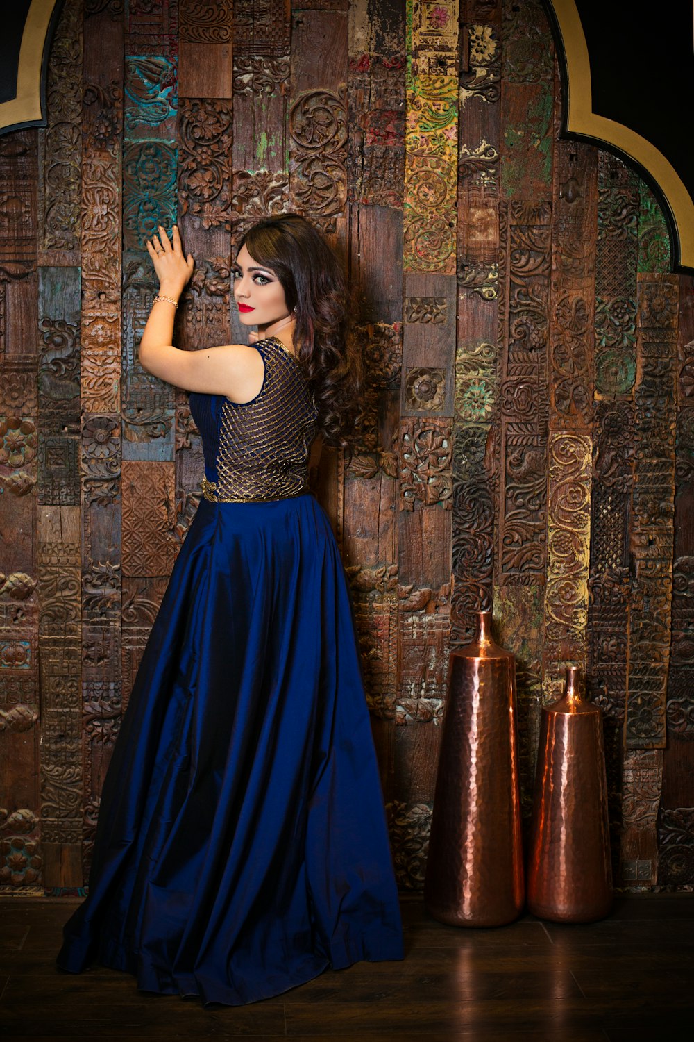 woman in blue dress standing near brown and blue floral wall