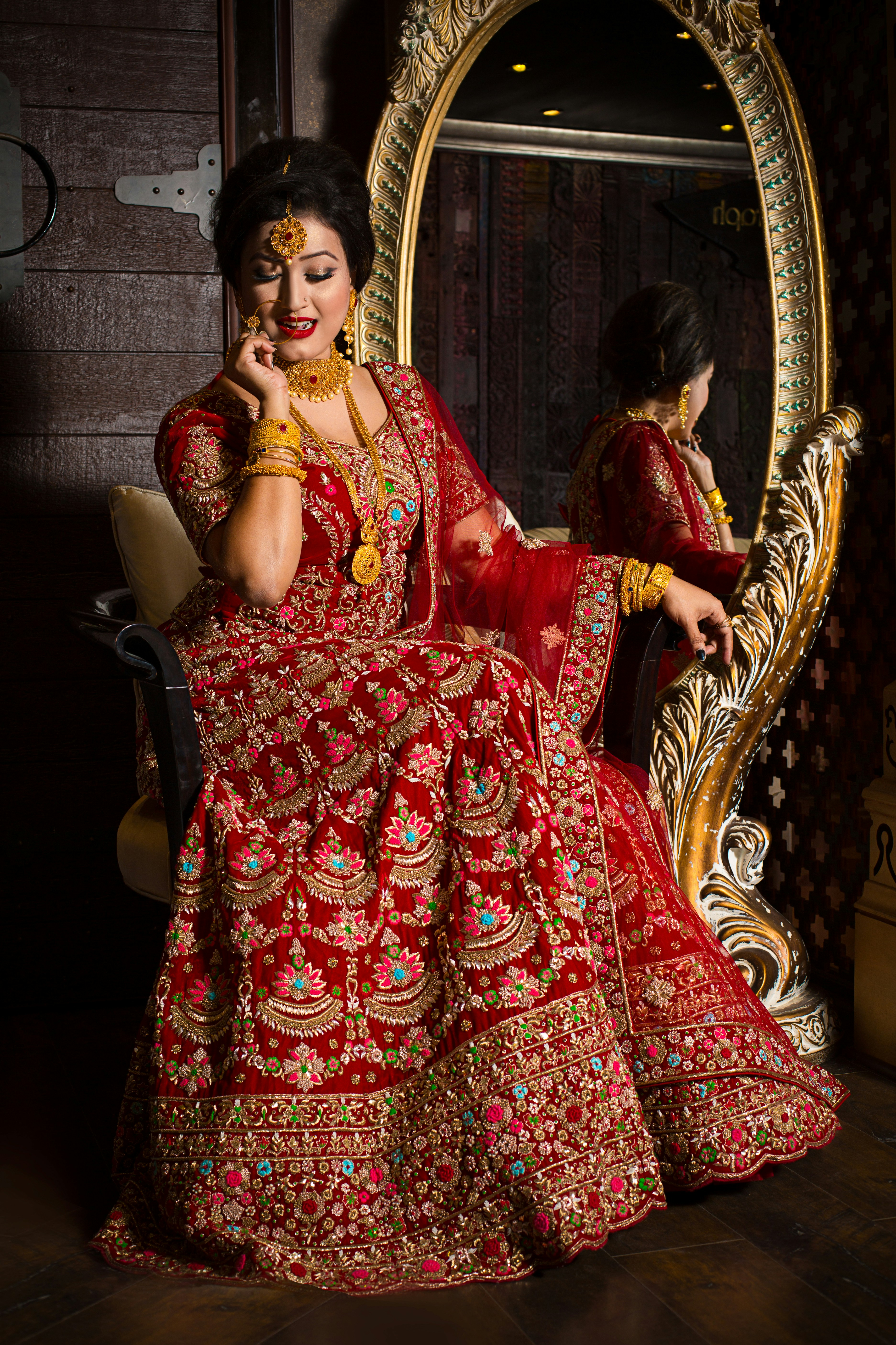 woman in red and gold floral dress sitting on brown wooden armchair