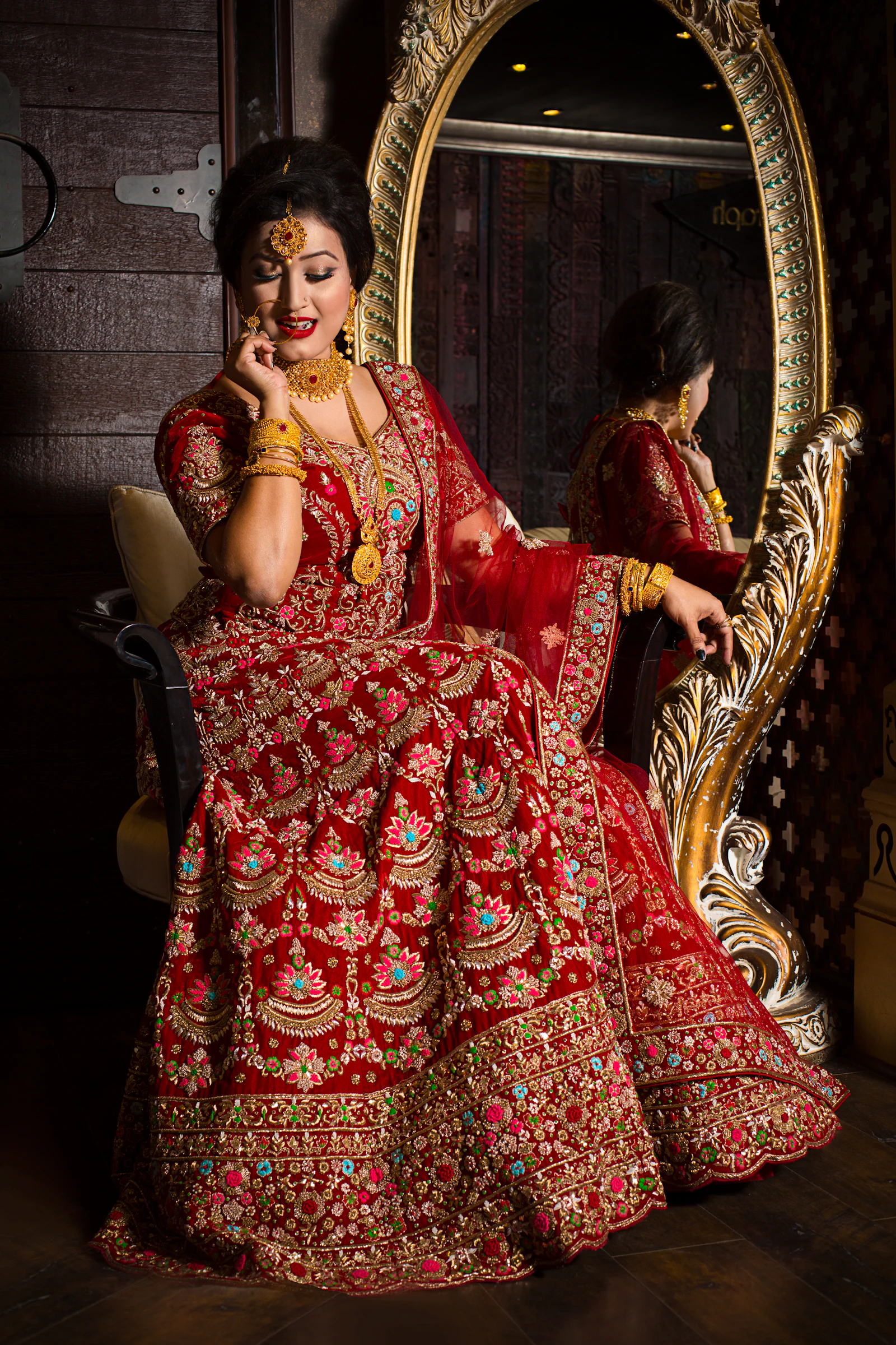 Bride seated on an ornate chair in a red embroidered lehenga