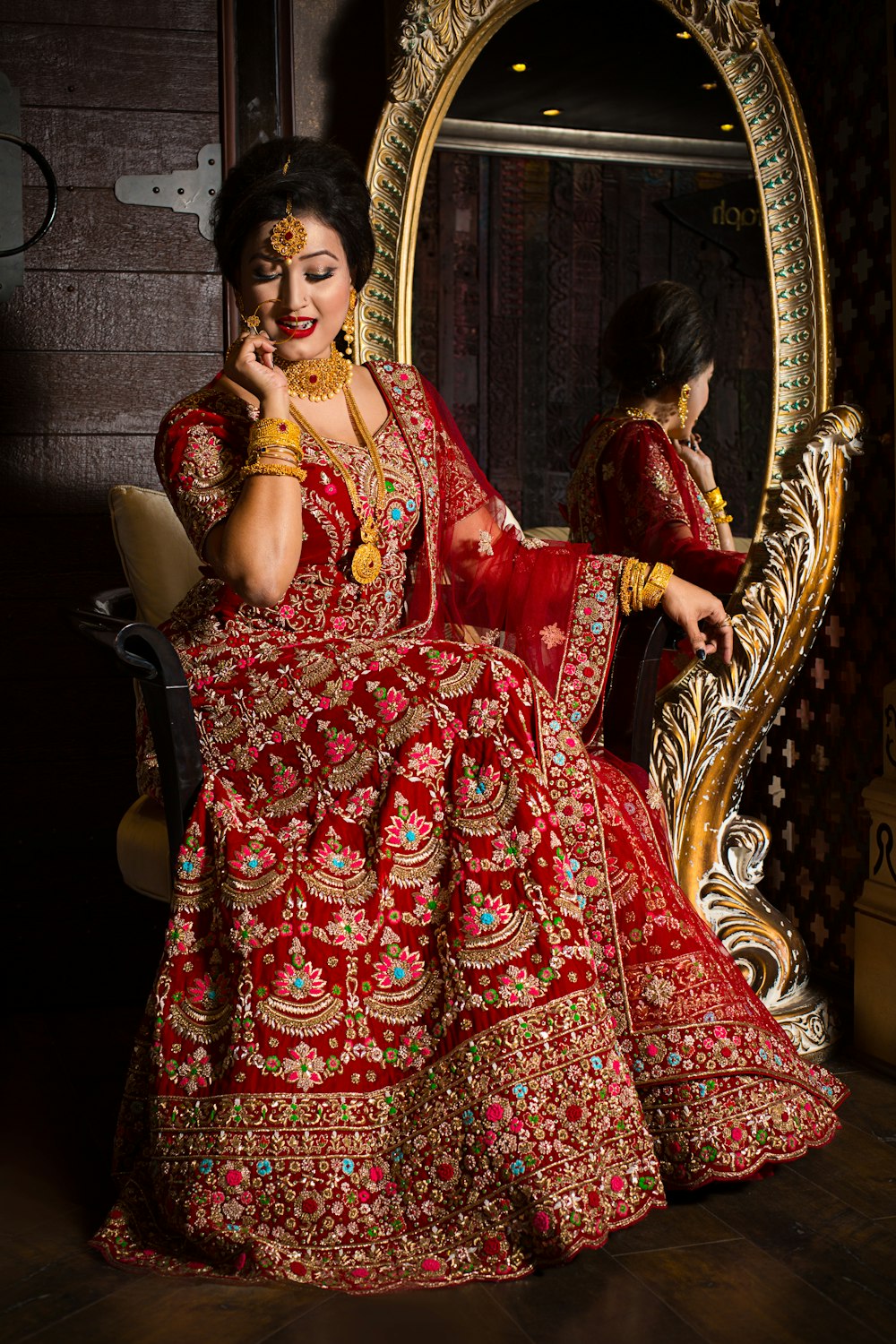 woman in red and gold floral dress sitting on brown wooden armchair