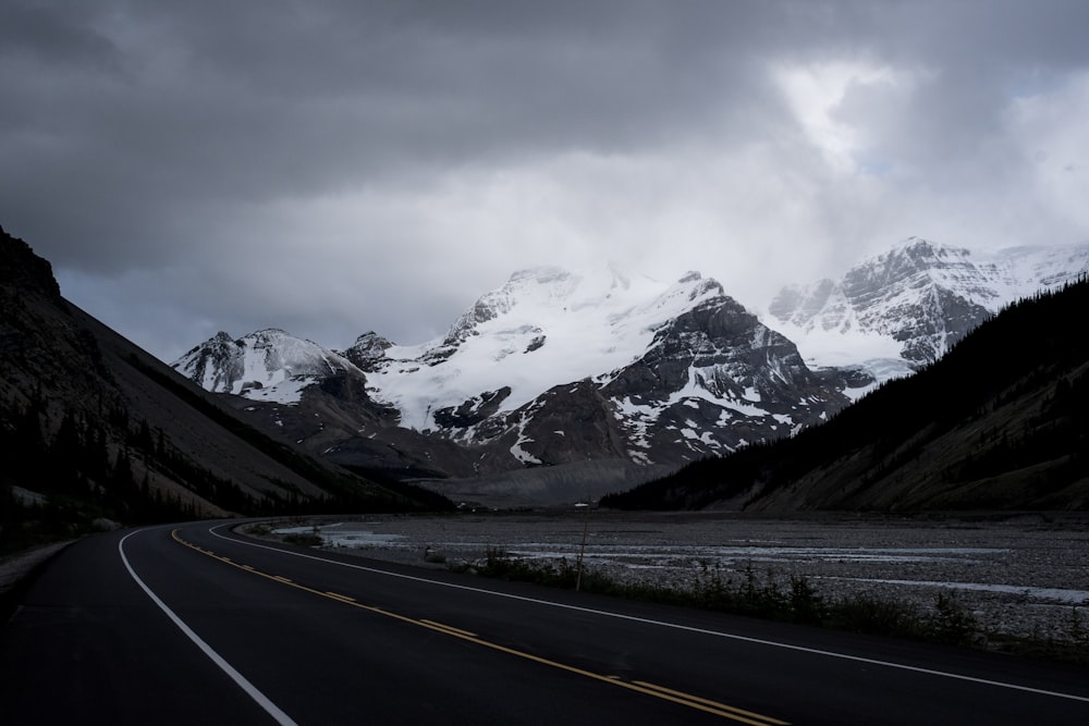 gray concrete road near snow covered mountain during daytime