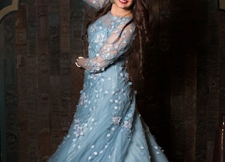 woman in white floral dress standing near brown wall