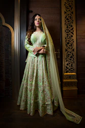 Elegant display of traditional salwar suits in deep peacock green and warm cream hues.