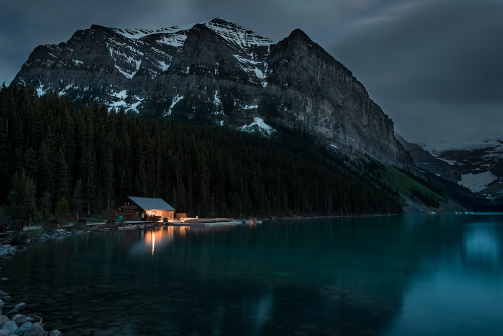 Casa di legno marrone sul lago vicino alla montagna