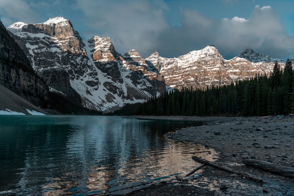 lake near trees and snow covered mountain during daytime