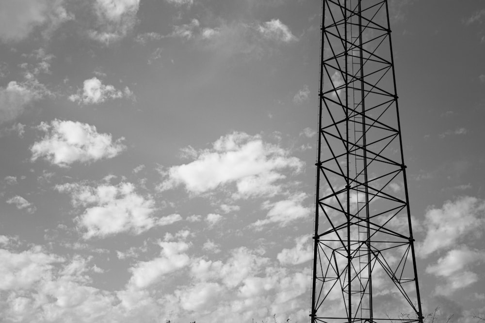grayscale photo of electric tower under cloudy sky