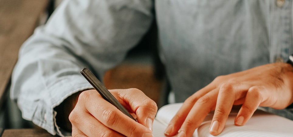 person in gray dress shirt writing on white paper