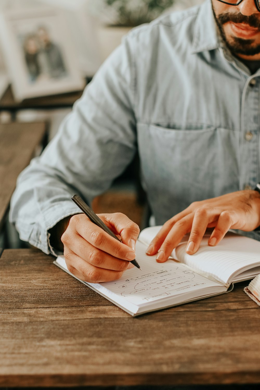 person in gray dress shirt writing on white paper