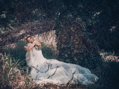 woman in white dress lying on ground covered with dried leaves