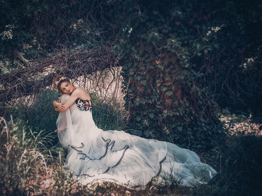 Frau in weißem Kleid liegt auf dem mit getrockneten Blättern bedeckten Boden