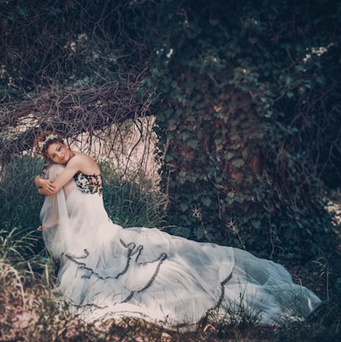 woman in white dress lying on ground covered with dried leaves