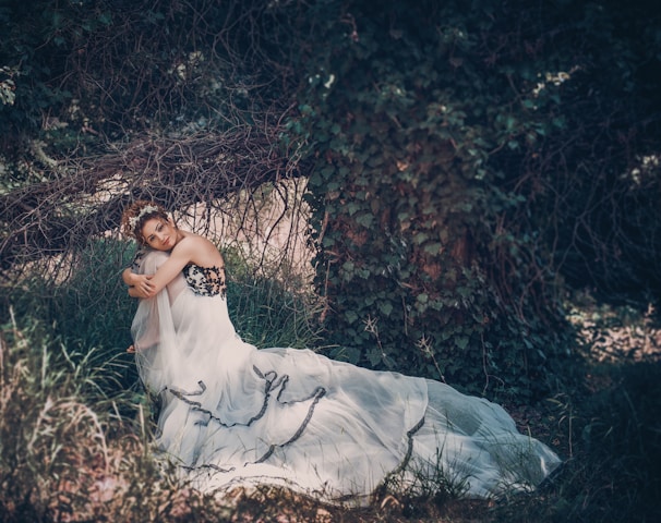 woman in white dress lying on ground covered with dried leaves