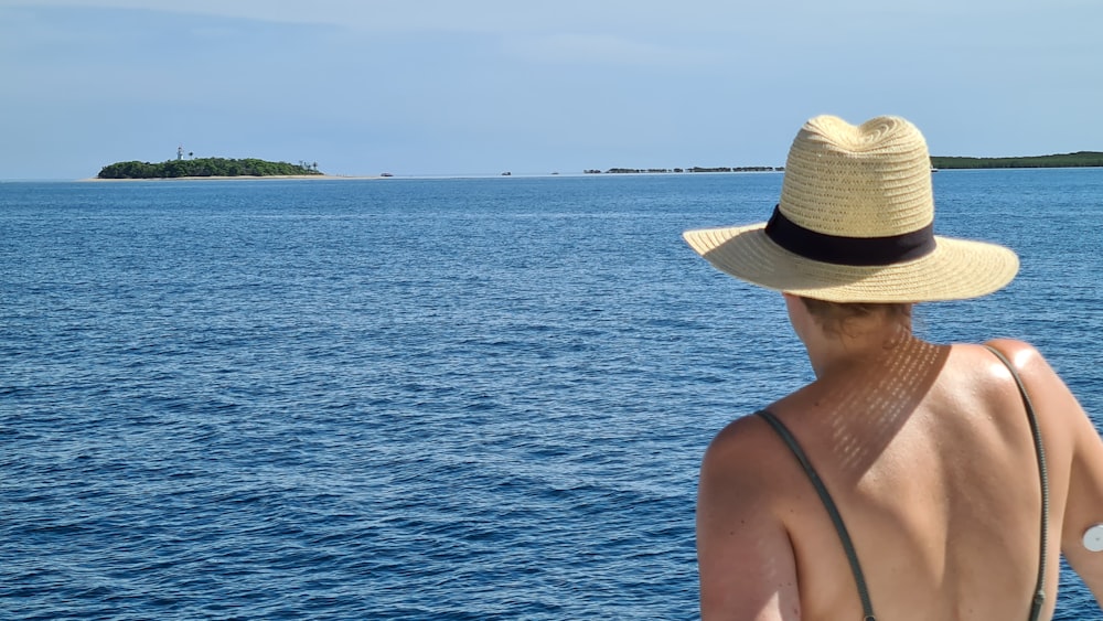 woman in brown sun hat standing near body of water during daytime