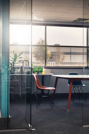 A professional cleaner in uniform carefully cleaning a modern office space with natural light.